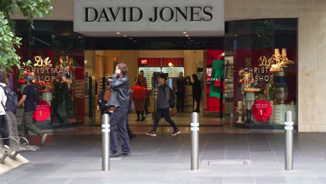 Toma-En-Cámara-Lenta-Que-Captura-El-Tráfico-Peatonal-De-La-Entrada-Principal-De-Los-Grandes-Almacenes-David-Jones-En-El-Bullicioso-Centro-De-La-Ciudad-De-Melbourne-Y-Los-Peatones-Paseando-Por-La-Calle-Bourke.