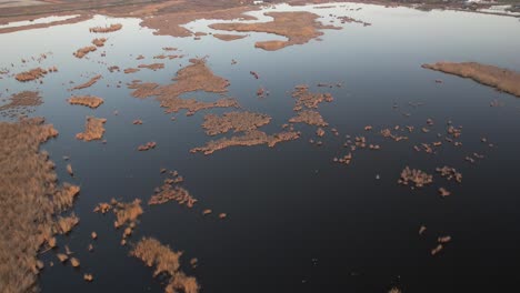 A-serene-delta-with-scattered-vegetation-during-sunset,-aerial-view