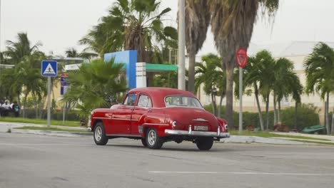 Red-Chevrolet-Styleline-1952-saloon-vintage-American-car-driving-away-in-Varadero,-Cuba,-panning-shot