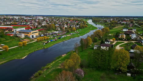 Aerial-village-divided-by-river,-houses-on-both-sides,-Bauska-Latvia