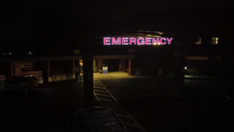 Aerial-orbit-shot-of-lighting-Emergency-Sign-on-entrance-of-Hospital-at-night