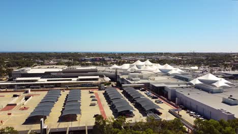 Toma-Aérea-Inversa-Del-Aparcamiento-Y-Edificios-De-La-Azotea-Del-Centro-Comercial-Junto-Al-Lago-Joondalup-Perth