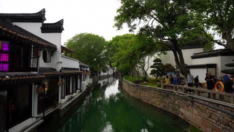 Gente-Junto-Al-Canal-En-Los-Jardines-Clásicos-De-Suzhou-En-Jiangsu,-China