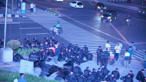 Riot-Police-officers-resting,-dark-city-square,-transportation-movement