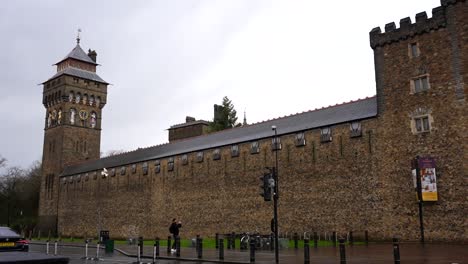 Tourist-walking-and-taking-photos-of-Cardiff-Castle-on-rainy-day,-UK