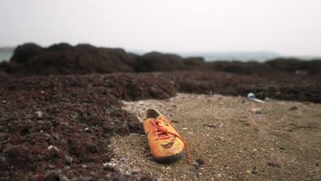 Leuchtend-Orange-Sneaker-Zurückgelassen-An-Einem-Felsigen-Strand