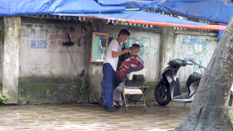 Street-barber-business,-motorbike-seated-customer,-speeding-traffic