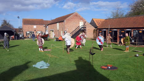 Vikings-medieval-warriors-engage-in-a-historical-reenactment,-practicing-combat-techniques-with-shields-and-spears-in-a-rustic-courtyard