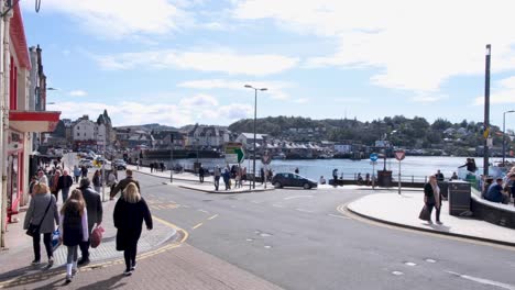 Busy-crowds-of-people-walking-along-the-waterfront-visiting-the-popular-holiday-destination-of-Oban-in-western-Scotland-UK