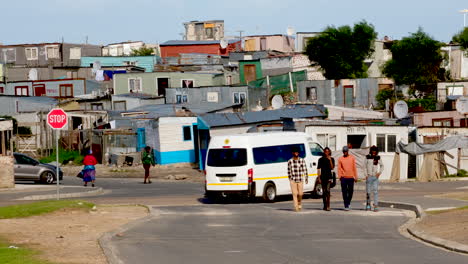 Taxi-drives-past-group-of-black-teenagers-in-township-with-makeshift-houses