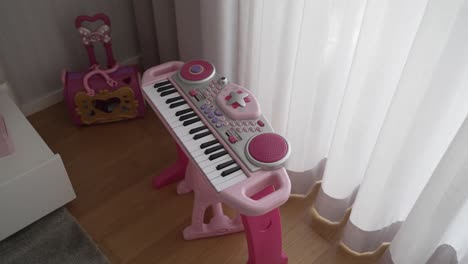 Colorido-Teclado-Infantil-Y-Equipaje-De-Juguete-En-Una-Luminosa-Sala-De-Juegos,-Que-Inspira-Creatividad-Musical-Y-Juego