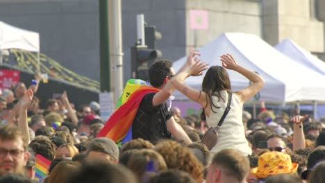 Young-couple-at-lively-street-festival,-woman-on-shoulders,-crowd-celebrating