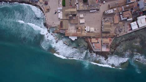 Aerial-top-down-static-gentle-waves-crashing-into-old-town,-Sicily