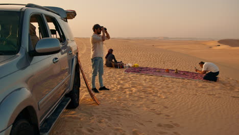 Men-setting-up-a-picnic-next-to-a-car-in-the-Sahara-Desert