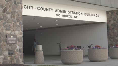 City-and-County-Administration-Building-in-downtown-Grand-Rapids,-Michigan-with-people-waking-out-and-stable-wide-shot