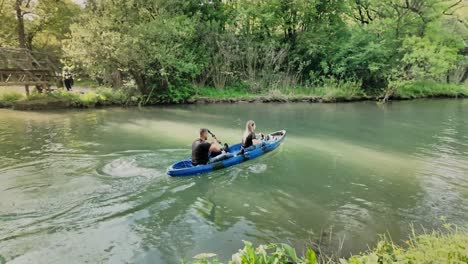 Canoe-couple-paddle-under-rustic-wooden-bridge-on-Zlatna-Panera-river