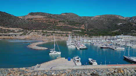 Malerische-Luftaufnahme-Des-Yachthafens-Port-Ginesta-Mit-Booten-Und-Den-Umliegenden-Hügeln-In-Barcelona