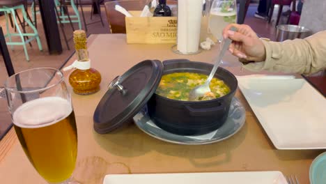 Static-view-of-woman's-hand-stirring-a-hot-soup-from-the-pot-in-a-restaurant