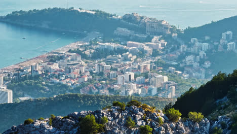 Telephoto-drone-shot-of-the-Bečići-city-from-the-mountains,-in-sunny-Montenegro