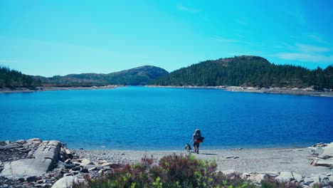 Un-Excursionista-Y-Su-Malamute-De-Alaska-Toman-Un-Descanso-A-Orillas-Del-Lago---Toma-Estática