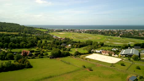 Luftaufnahme-Einer-Grünen-Sommerlandschaft-Mit-Einer-Pferderennbahn-Und-Einem-Pferdekoppel-In-Der-Nähe-Des-Meeres-In-Der-Normandie,-Frankreich