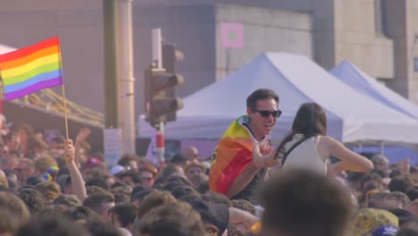 Crowd-celebrating-at-pride-event-with-rainbow-flags,-urban-background