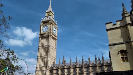 Vista-Icónica-Del-Big-Ben-Y-Las-Casas-Del-Parlamento-Bajo-Un-Cielo-Azul-Con-Nubes-Dispersas,-Con-Un-Vistazo-Del-London-Eye