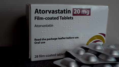 A-close-up-of-a-box-of-Atorvastatin-20-mg-with-an-opened-blister-pack-of-film-coated-tablets-in-the-foreground