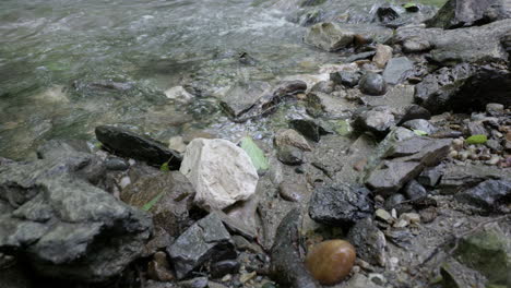 Wasser-Gurgelt-In-Einem-Gebirgsbach,-Mit-Felsen-Und-Einem-Kieselstrand