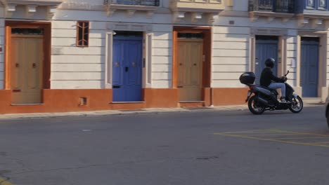 A-moped-driver-navigates-the-narrow-streets-and-alleys-of-Valletta,-Malta