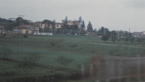 Suburban-Landscape-Through-a-Train-Window-Under-a-Cloudy-Sky