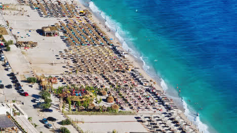 Telephoto-drone-shot-of-large-waves-at-a-beach-resort-in-Albania,-sunny-day