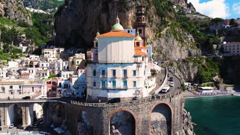 Aerial-Boom-Shot-Above-Atrani-as-Cars-Drive-along-Amalfi-Coast,-Italy