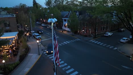 Verkehr-Auf-Der-Straße-Mit-Wehender-Amerikanischer-Flagge-In-Der-Abenddämmerung