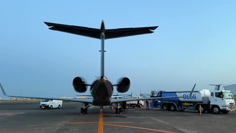 Rear-view-fueling-a-private-jet,-airplane-taking-off-in-background,-Tokyo