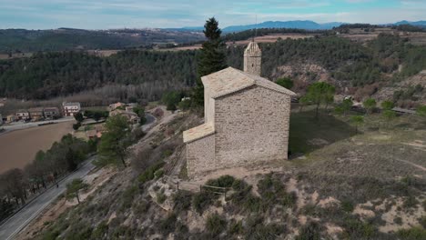 An-ancient-stone-church-in-the-old-town-of-oristas,-surrounded-by-scenic-hills,-aerial-view