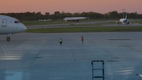 Empleados-De-Air-Canada-Caminando-Mientras-Un-Avión-Pasa-Detrás-En-El-Aeropuerto-Internacional-Trudeau-De-Montreal