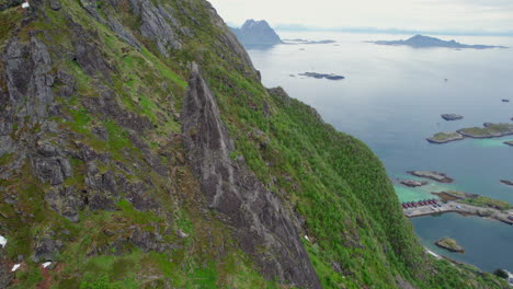 Vista-Aérea-En-órbita-Sobre-El-Pináculo-Rocoso-De-Svolvaergeita-Y-Donde-Se-Puede-Ver-A-Un-Escalador-A-Lo-Lejos.