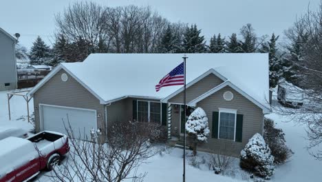 American-flag-in-front-of-house-in-neighborhood-during-snowy-winter-day