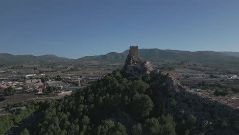 Castillo-Medieval-En-Lo-Alto-De-Una-Colina-Rodeada-De-Exuberante-Vegetación-Y-Una-Pintoresca-Ciudad-En-Biar,-Alicante,-España