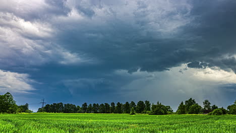 Dramatic-storm-clouds-gathering-over-lush-green-meadow-panorama,-time-lapse