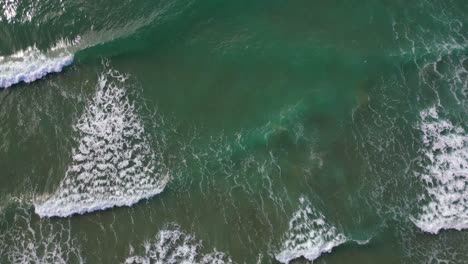 Waves-crashing-on-the-shore-of-the-coast-of-Port-Ginesta-in-Barcelona,-aerial-view