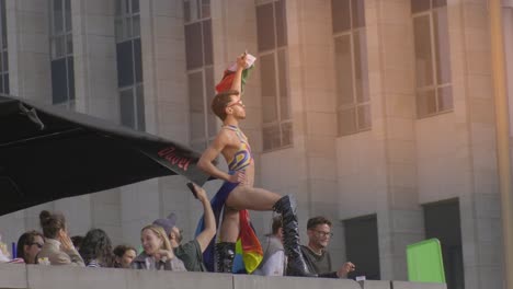 Drag-queen-holding-Palestine-flag-during-pride-event,-urban-background