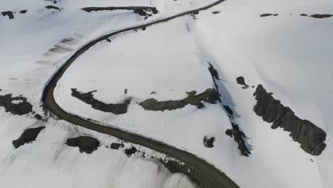 Toma-Aérea-De-Pájaro-De-La-Carretera-Entre-Montañas-Nevadas-En-La-Isla-De-Islandia