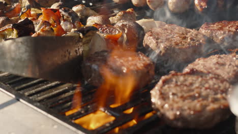 Llamas-Calientes-En-La-Barbacoa-Con-El-Chef-Volteando-Hamburguesas-De-Carne-Con-Salchichas-Y-Pinchitos-De-Pollo-Y-Verduras.