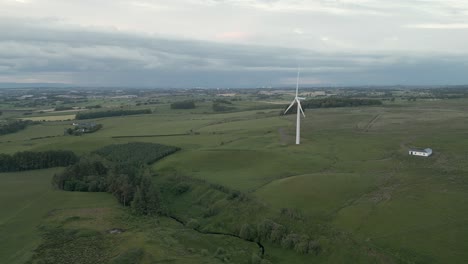 Aerial-orbits-wind-turbine-spinning-over-hazy-rolling-Scottish-country