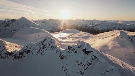 Man-reaching-snowy-mountain-peak-in-Norway,-aerial-view