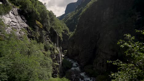 Deep-mountain-valley-with-flowing-river-in-Norway,-aerial-view