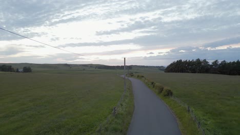 Slow-aerial-tracks-narrow-country-road-in-misty-Scottish-countryside