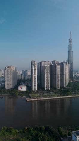 Landmark-building-on-the-Saigon-River-with-clear-blue-sky-vertical-drone-tracking-shot